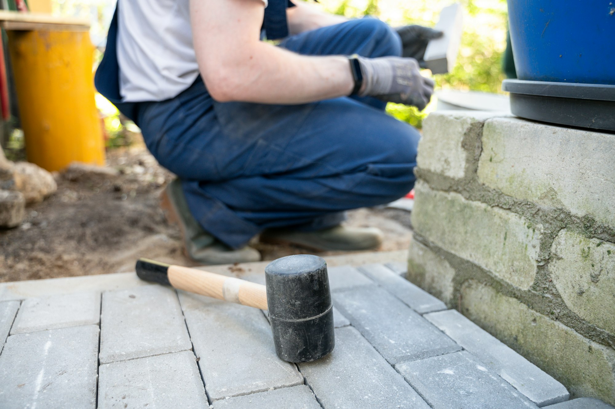 Worker laying paving stones with rubber mallet